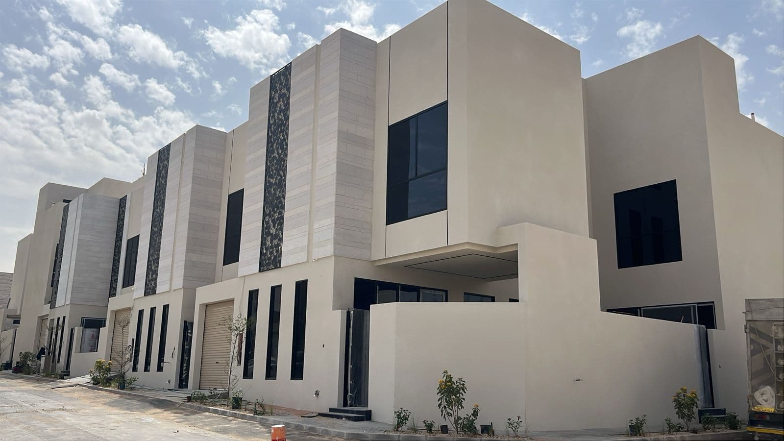 فلل سكنية حديثة باللون البيج تتميز بنوافذ سوداء كبيرة وتصاميم معمارية عصرية وأنيقة.